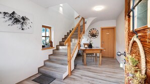 A staircase with wooden railings leading to a second floor, a wooden door, and a wall-mounted clock. - Apartment 'Ferienwohnung Unternberg' with Mountain View, Shared Terrace and Wi-Fi (Ruhpolding)