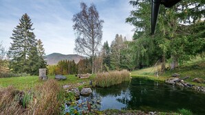 A serene outdoor setting with a pond, trees, and a wooden structure. - Apartment 'Ferienwohnung Unternberg' with Mountain View, Shared Terrace and Wi-Fi (Ruhpolding)