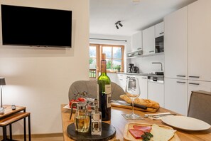 A modern kitchen with a dining table set for a meal, a bottle of wine, and a glass of wine.