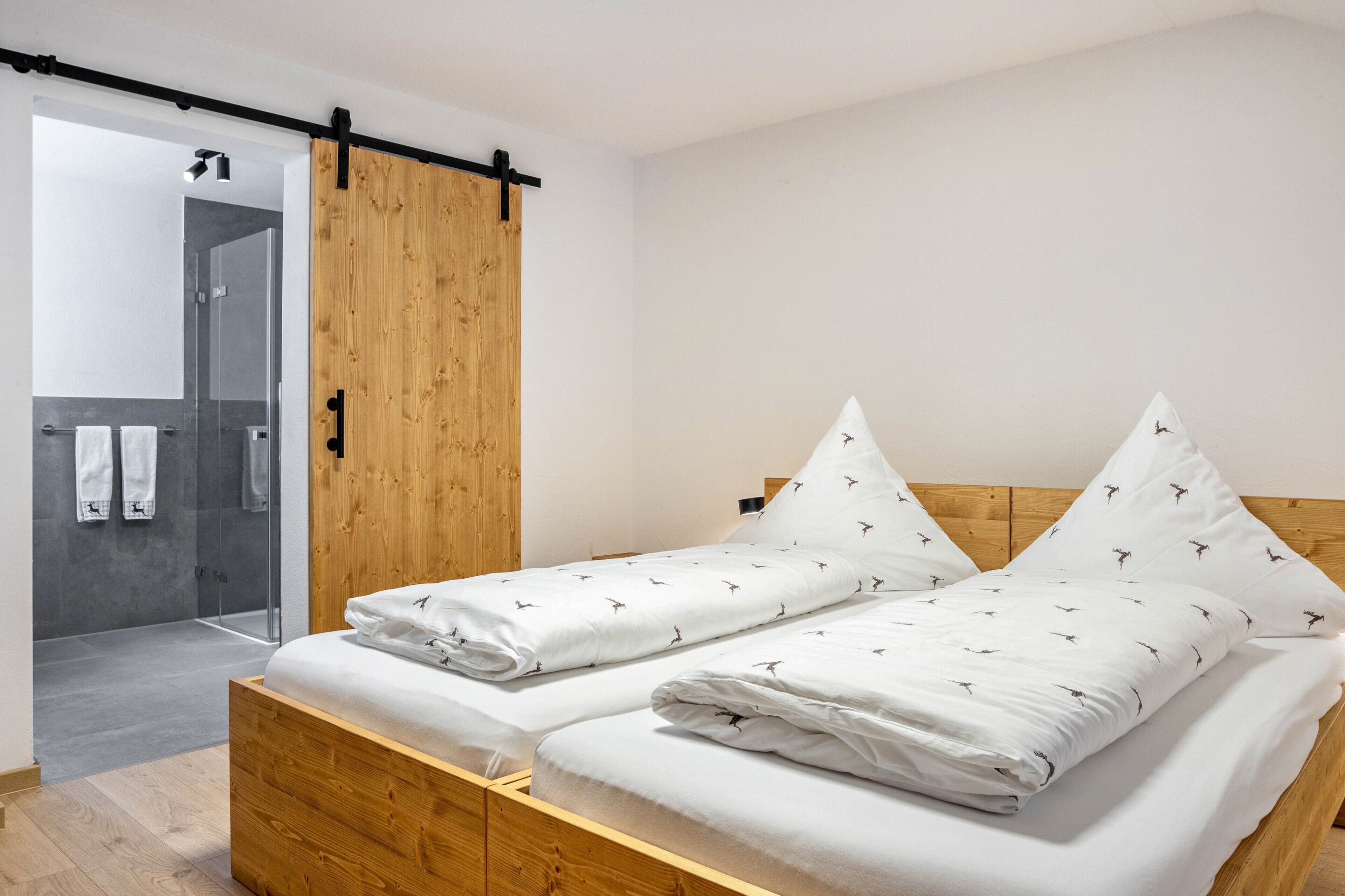 A modern bedroom with a wooden bed, a sliding door, and a shower area.