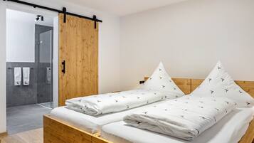 A modern bedroom with a wooden bed, a sliding door, and a shower area.