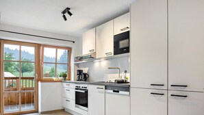 A modern kitchen with a large window, built-in oven, and white cabinetry.
