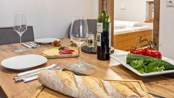 Una tavola imbandita con piatti, posate, una bottiglia di vino, una pagnotta e un piatto di verdure.