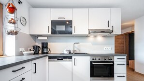 A modern kitchen with white cabinets, a built-in microwave, a stove, and a dishwasher.