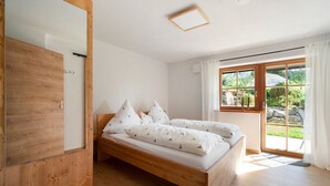A bedroom with a wooden bed, a large window, and a door. - Apartment 'Wiesengrund' with Garden View, Private Terrace and Shared Garden (Dietmannsried)
