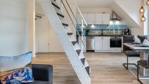 Una cocina moderna con armarios blancos, una campana extractora de acero inoxidable y un comedor con mesa y sillas.