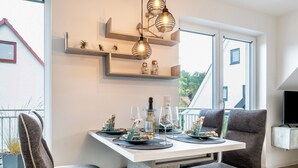 Un comedor moderno con una mesa blanca, sillas grises e iluminación colgante.