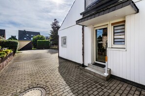 A white building with a paved driveway and a small set of steps leading to a door. - Holiday Home 'Lichtblick' with Private Terrace, Shared Garden, and Wi-Fi (Bottrop)