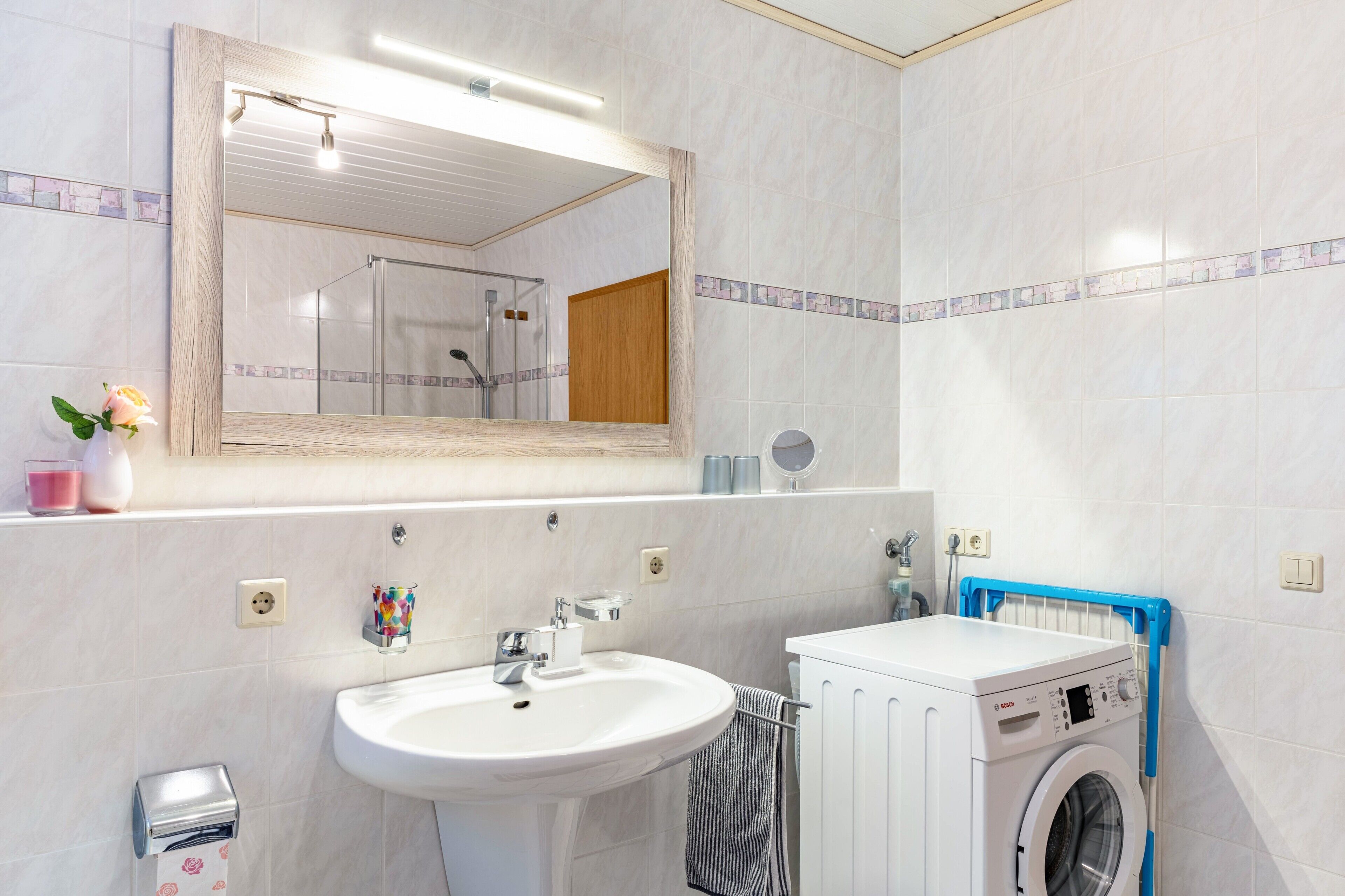 A bathroom with a sink, mirror, and a washing machine.