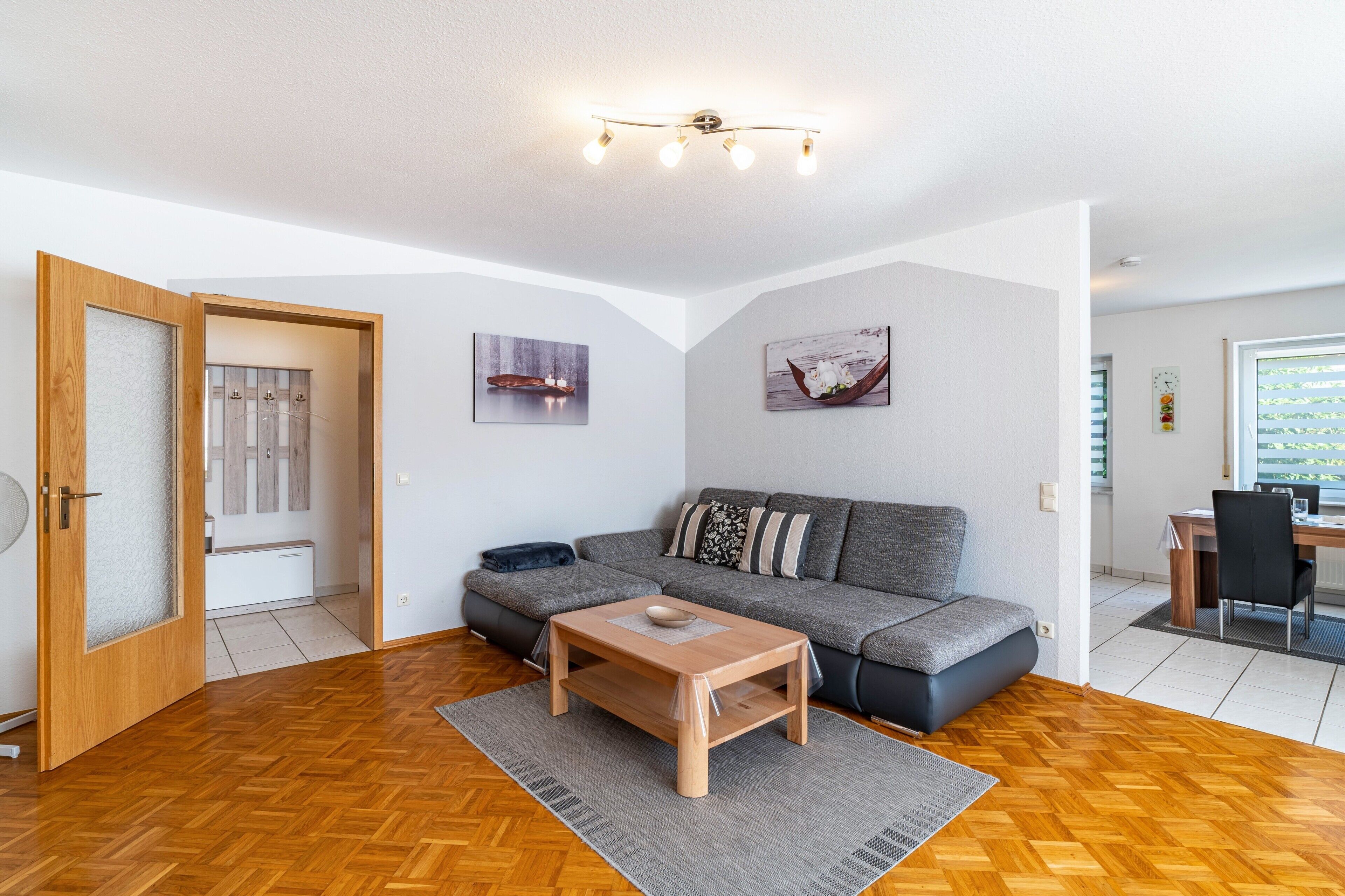Una sala de estar moderna con un sofá, una mesa de centro de madera y un comedor con una mesa y sillas.