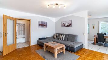 Una sala de estar moderna con un sofá, una mesa de centro de madera y un comedor con una mesa y sillas.