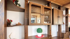A wooden cabinet with glass doors, a small potted plant, and decorative items on shelves.