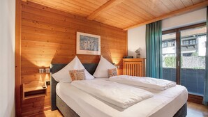 A wooden-paneled room with a bed, a nightstand, a framed picture, and a window with curtains.