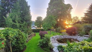 A garden with a pond, a wooden fence, and a house in the background.