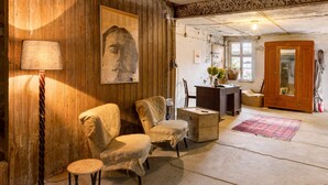 A rustic room with wooden walls, a wooden cabinet, a chair, a small table, and a lamp. - Guesthouse 'Schlamau19 - Under the Walnut Tree'
Apartment with 2 Guest Rooms, Shared Kitchen and Garden (Wiesenburg/Mark)
