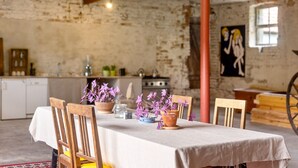 A dining table with chairs, potted plants, and a kitchen in the background. - Guesthouse 'Schlamau19 - Under the Walnut Tree'
Apartment with 2 Guest Rooms, Shared Kitchen and Garden (Wiesenburg/Mark)