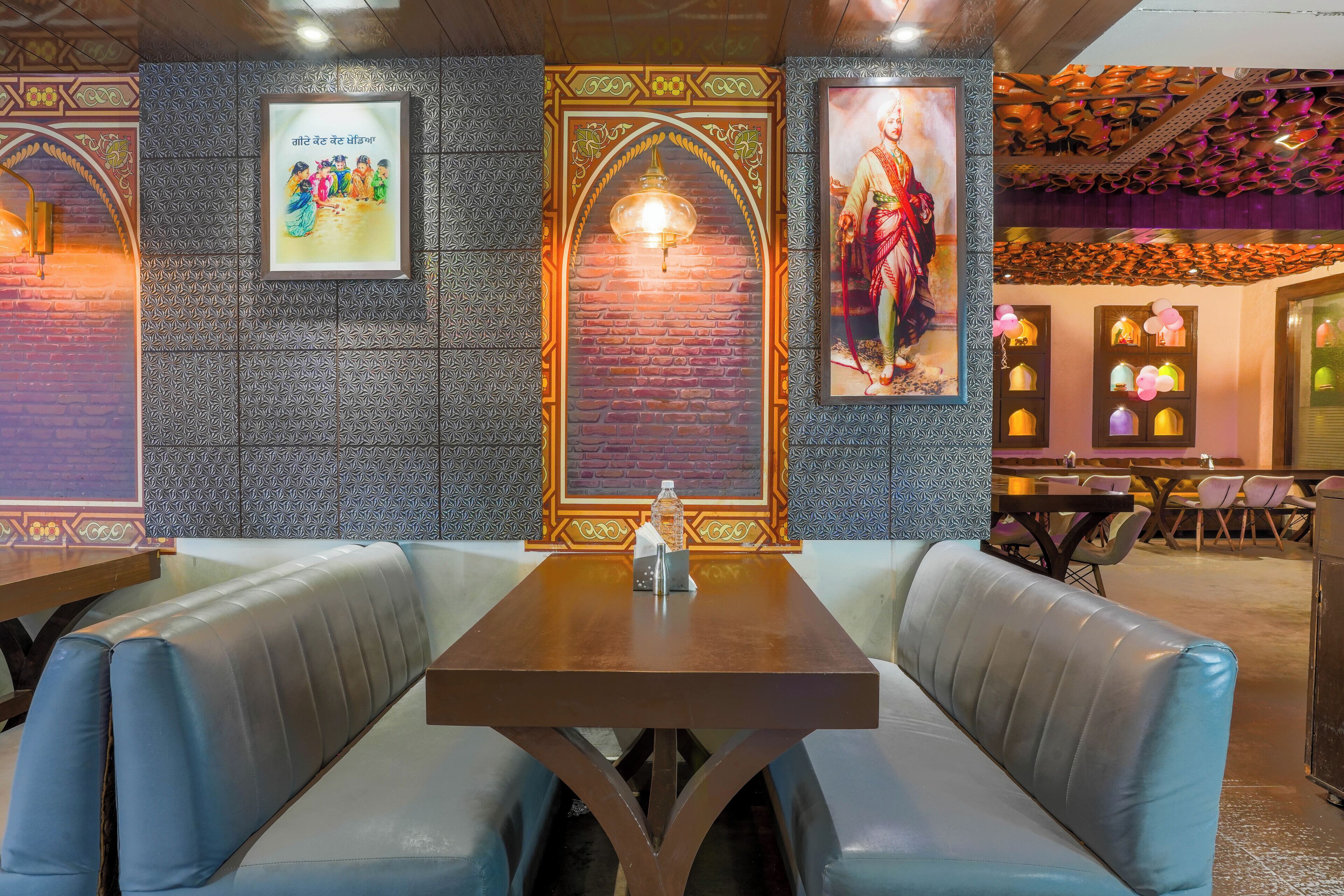 Interior de restaurante con pared de ladrillo, papel tapiz estampado y una mesa central con bancos.