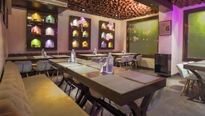 Ein Restaurant mit Sitzgelegenheiten in Form von Boxen, Tischen und einer Tonwanddecke.