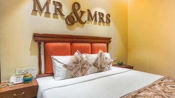 Habitación de hotel con cama, mesita de noche, teléfono y cartel en la pared que dice 'MR & MRS'.