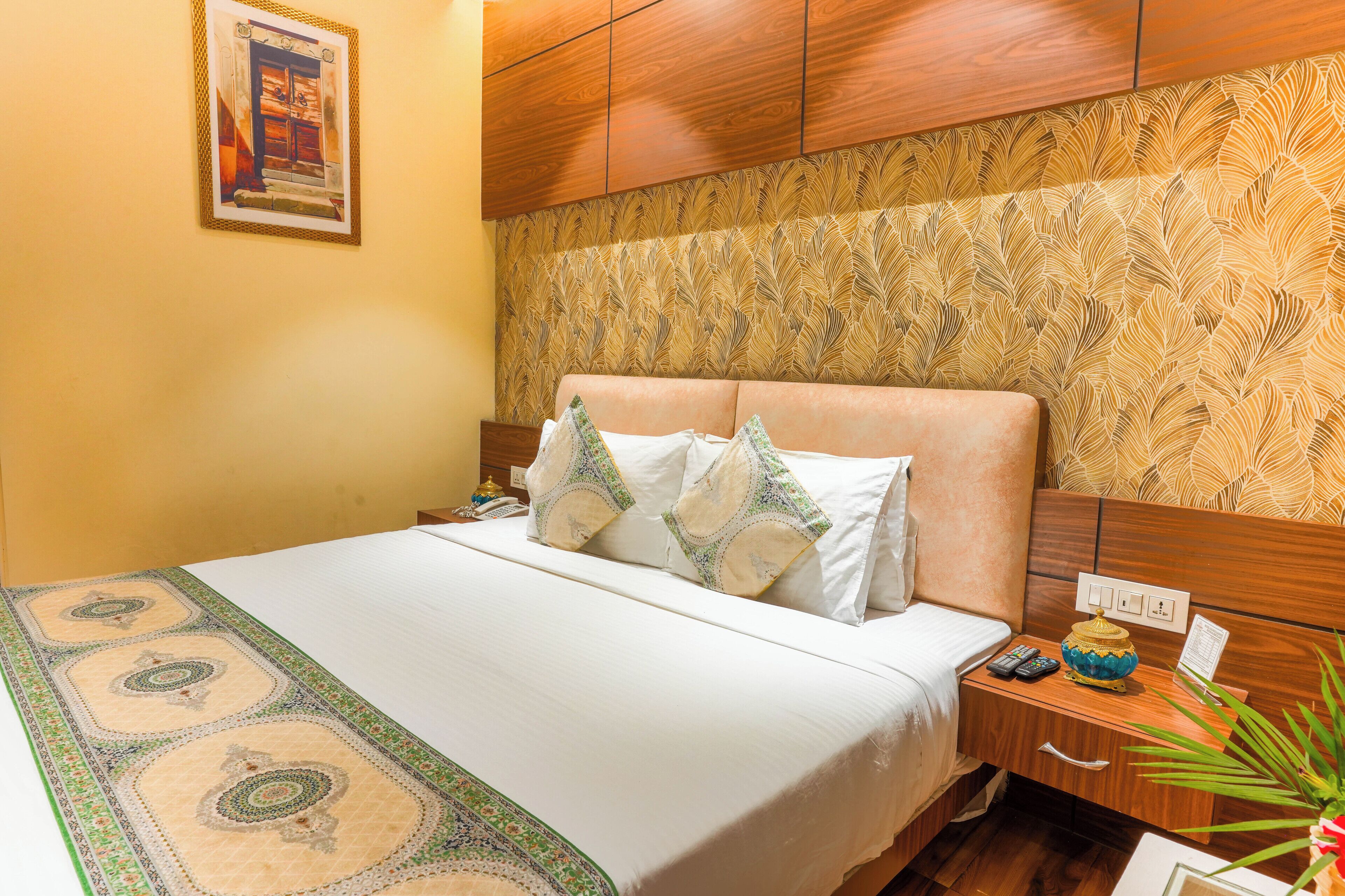 A hotel room with a bed, nightstand, and a decorative wall panel.