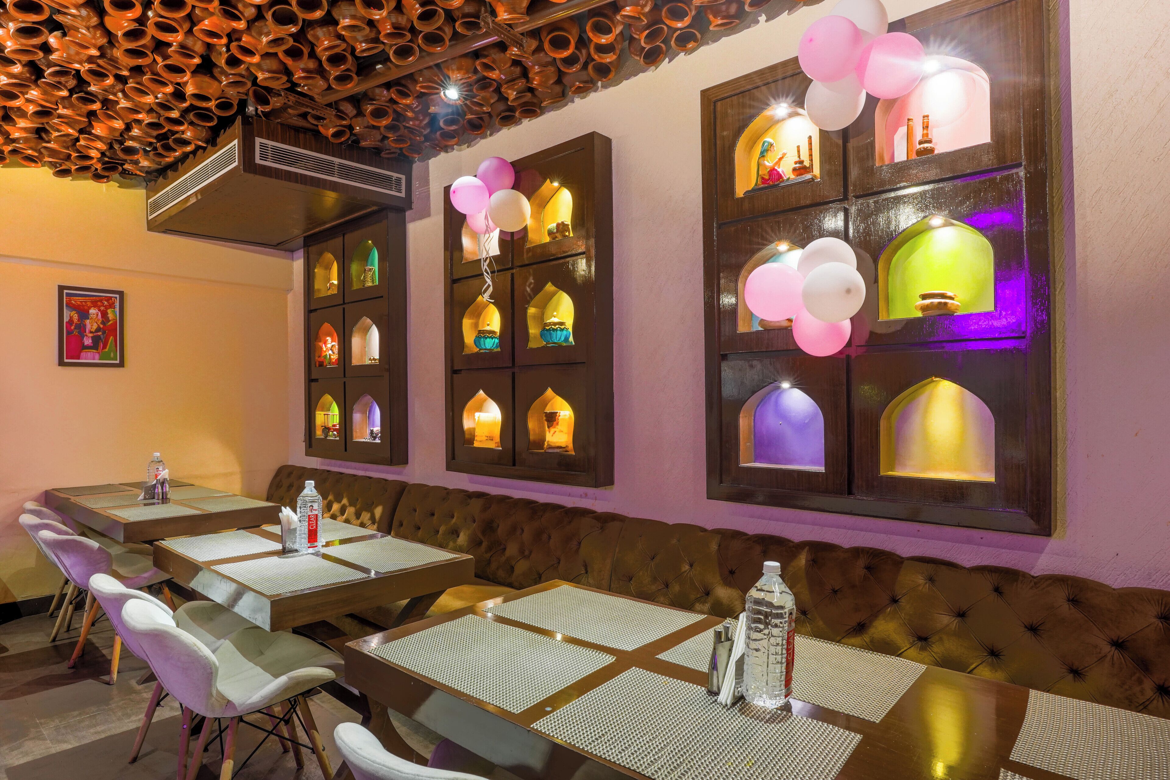 A restaurant with multiple tables and booths, decorative lighting, and a ceiling with a unique design.