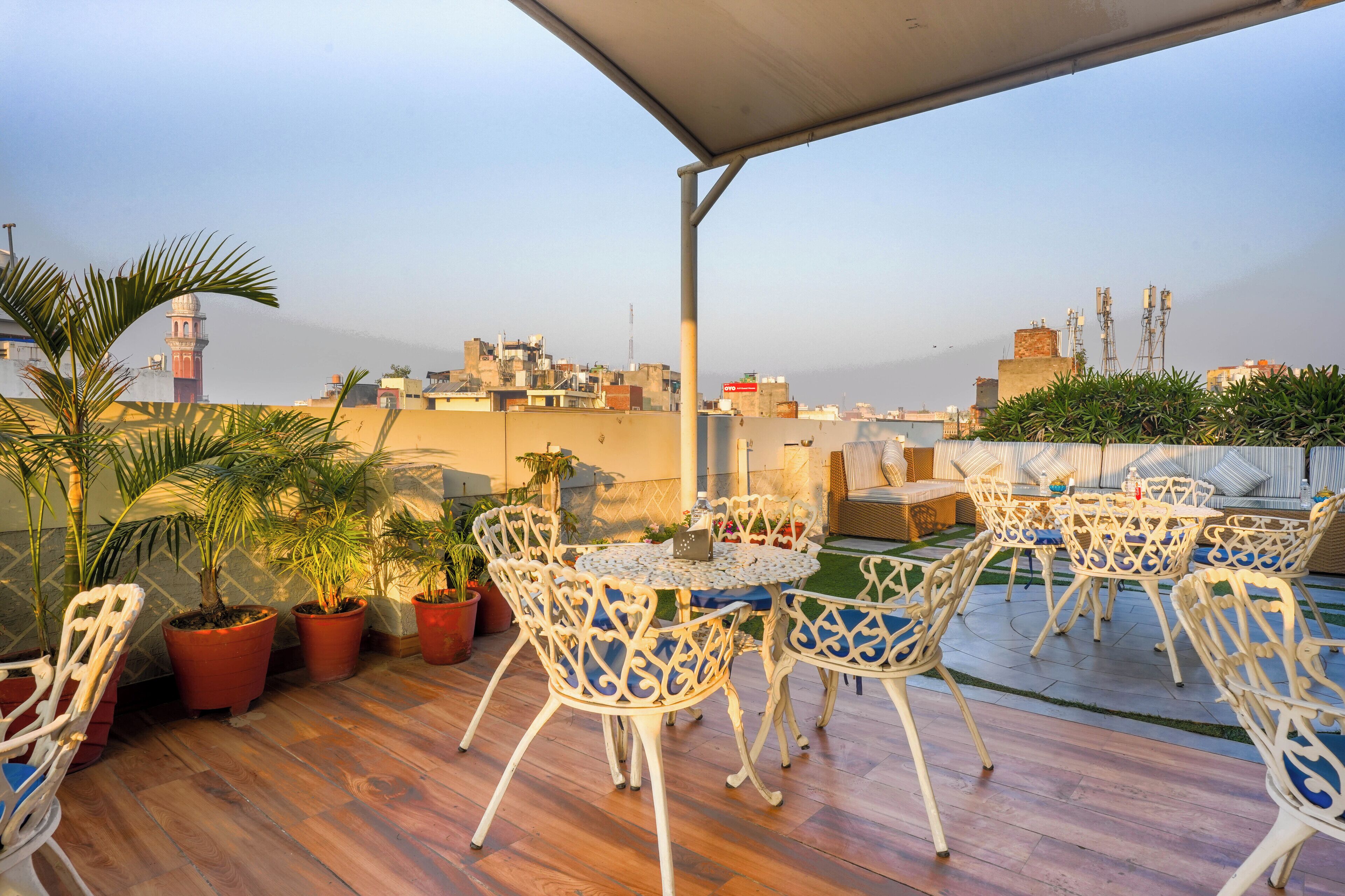 A rooftop terrace with outdoor seating, potted plants, and a view of the city skyline.