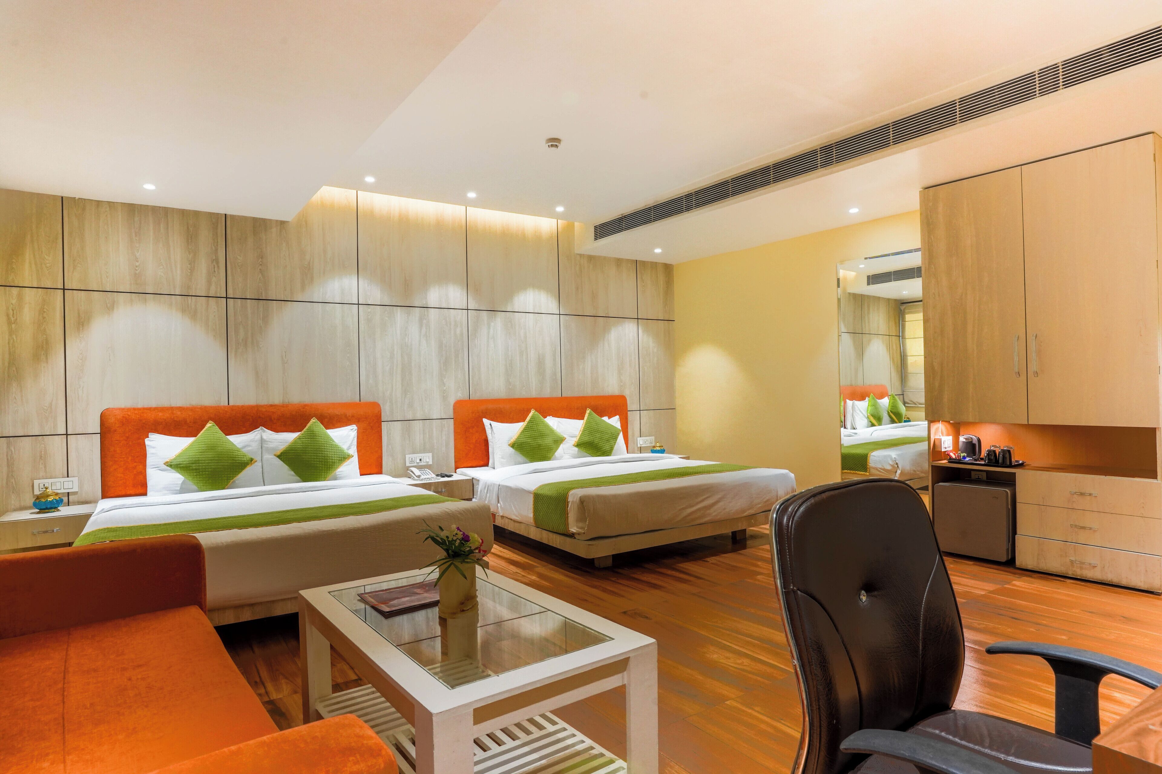 A hotel room with two beds, a sofa, a small table, and a chair.