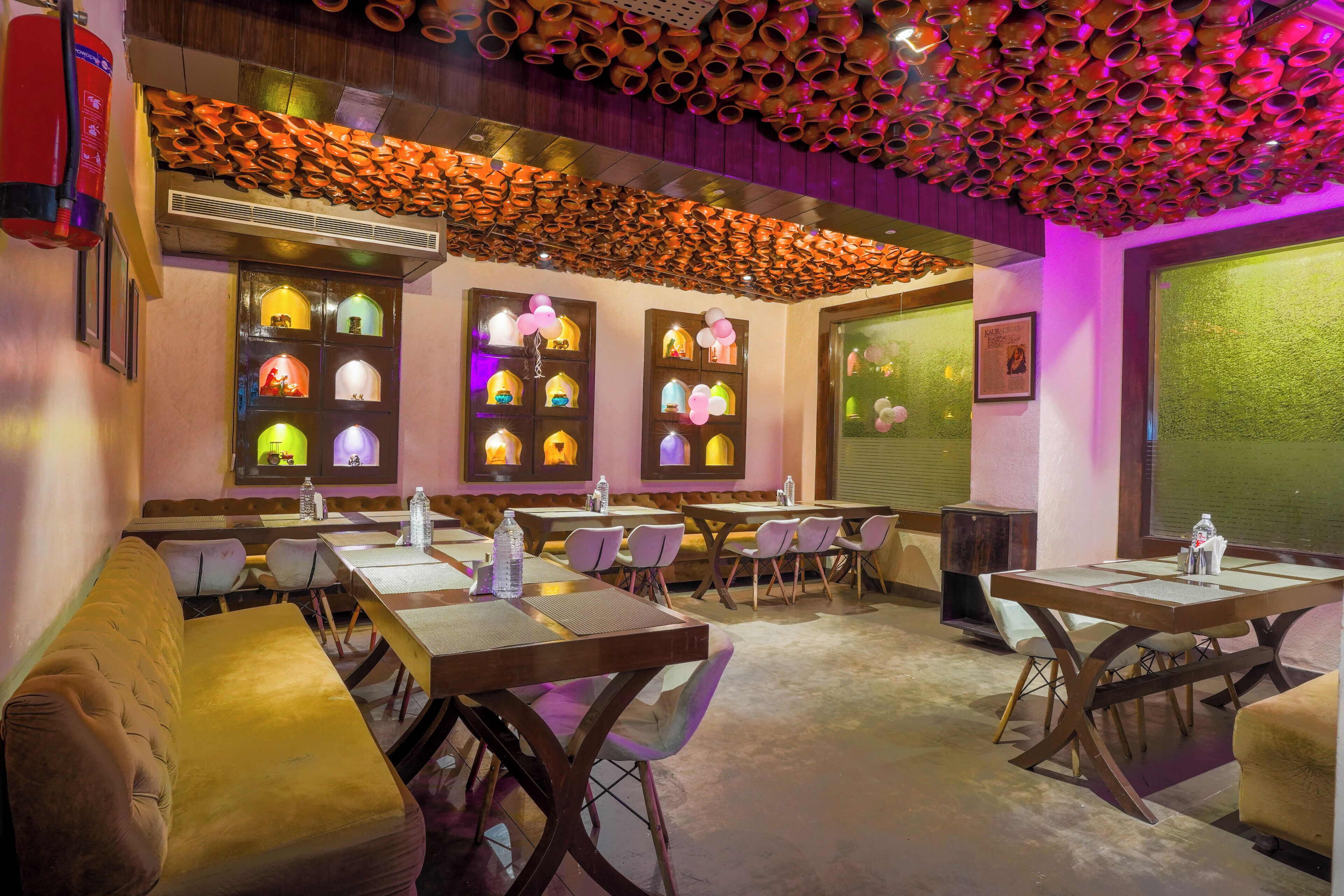 A restaurant with booths and tables, decorative wall sconces, and a ceiling with hanging pottery.