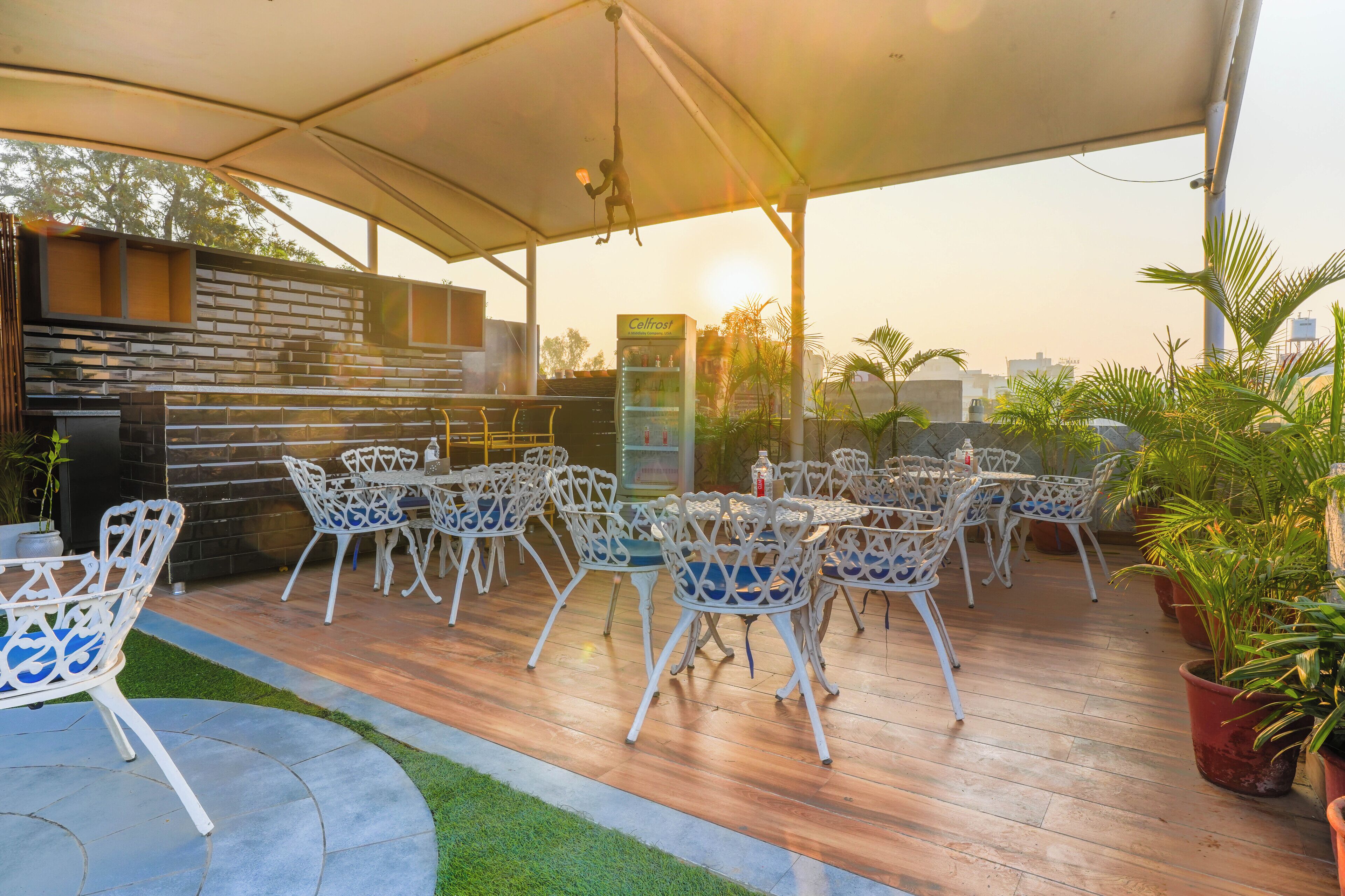 An outdoor patio with white metal chairs and tables, a stone wall, and a water dispenser.