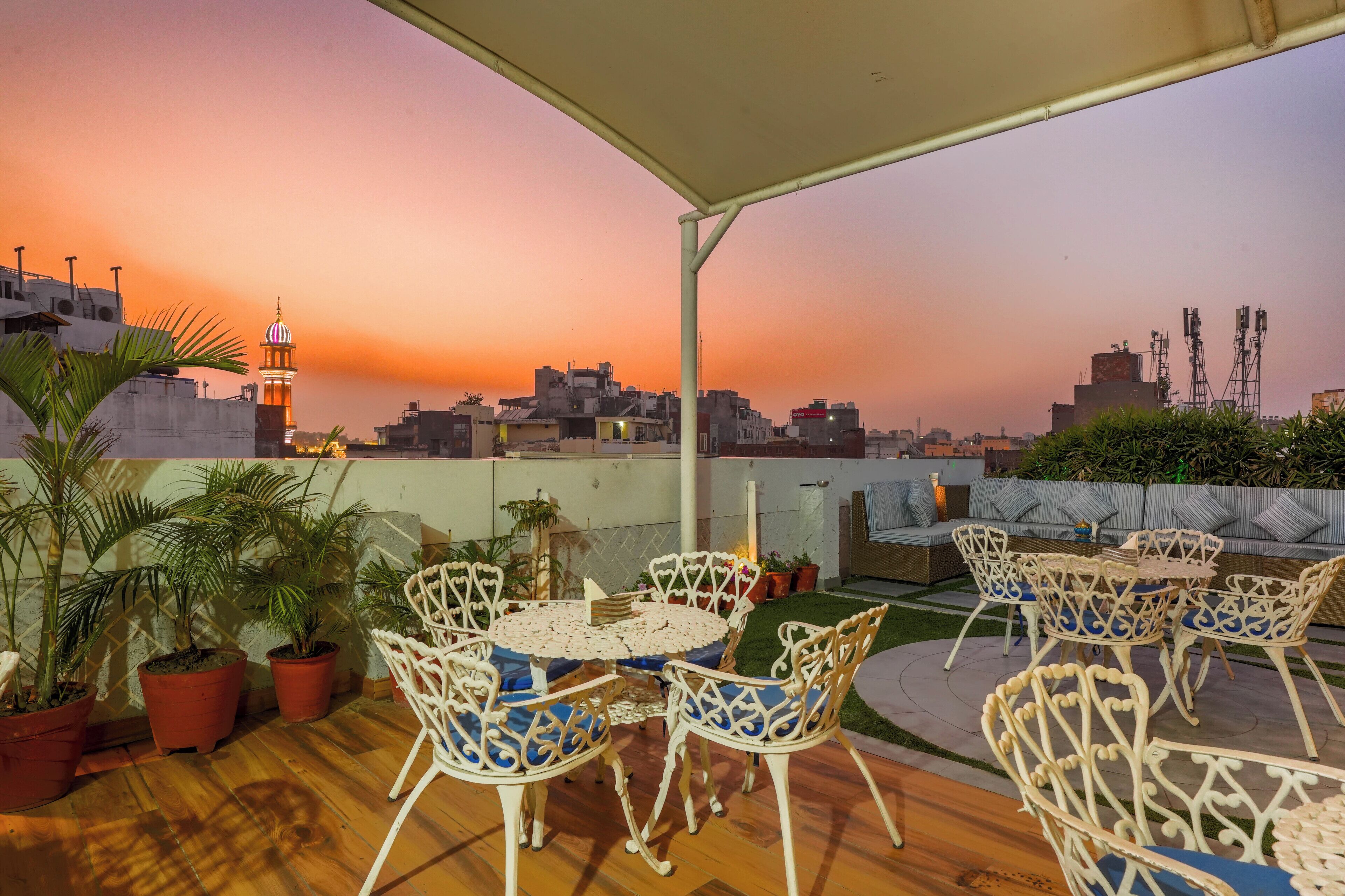 A rooftop terrace with a sunset view, outdoor seating, and potted plants.