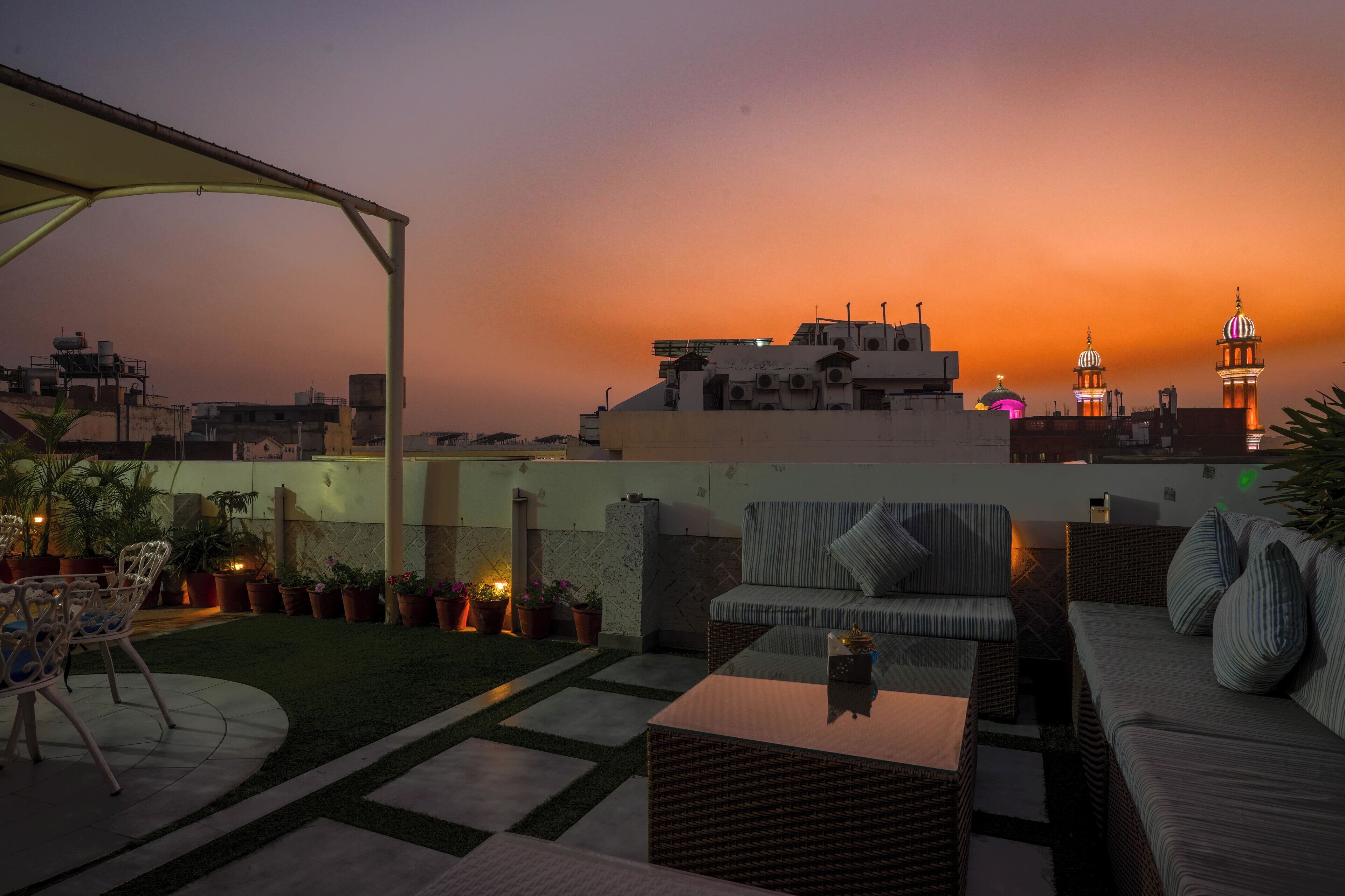 A rooftop terrace with outdoor furniture, a pergola, and potted plants.