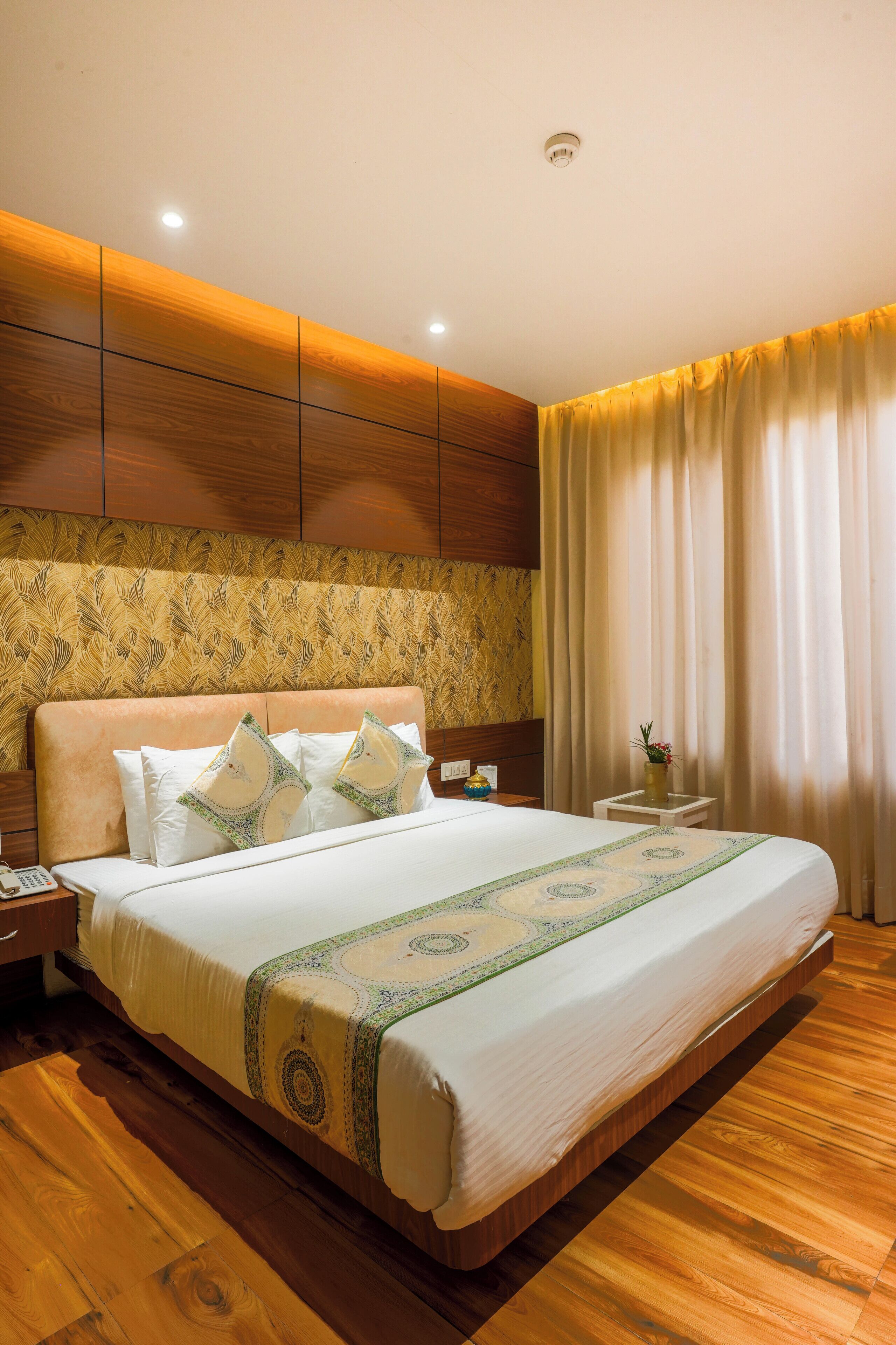 A hotel room with a large bed, wooden headboard, and a nightstand.