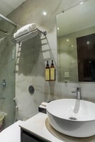 Un baño moderno con un espejo grande, un lavabo blanco y una cabina de ducha de vidrio.
