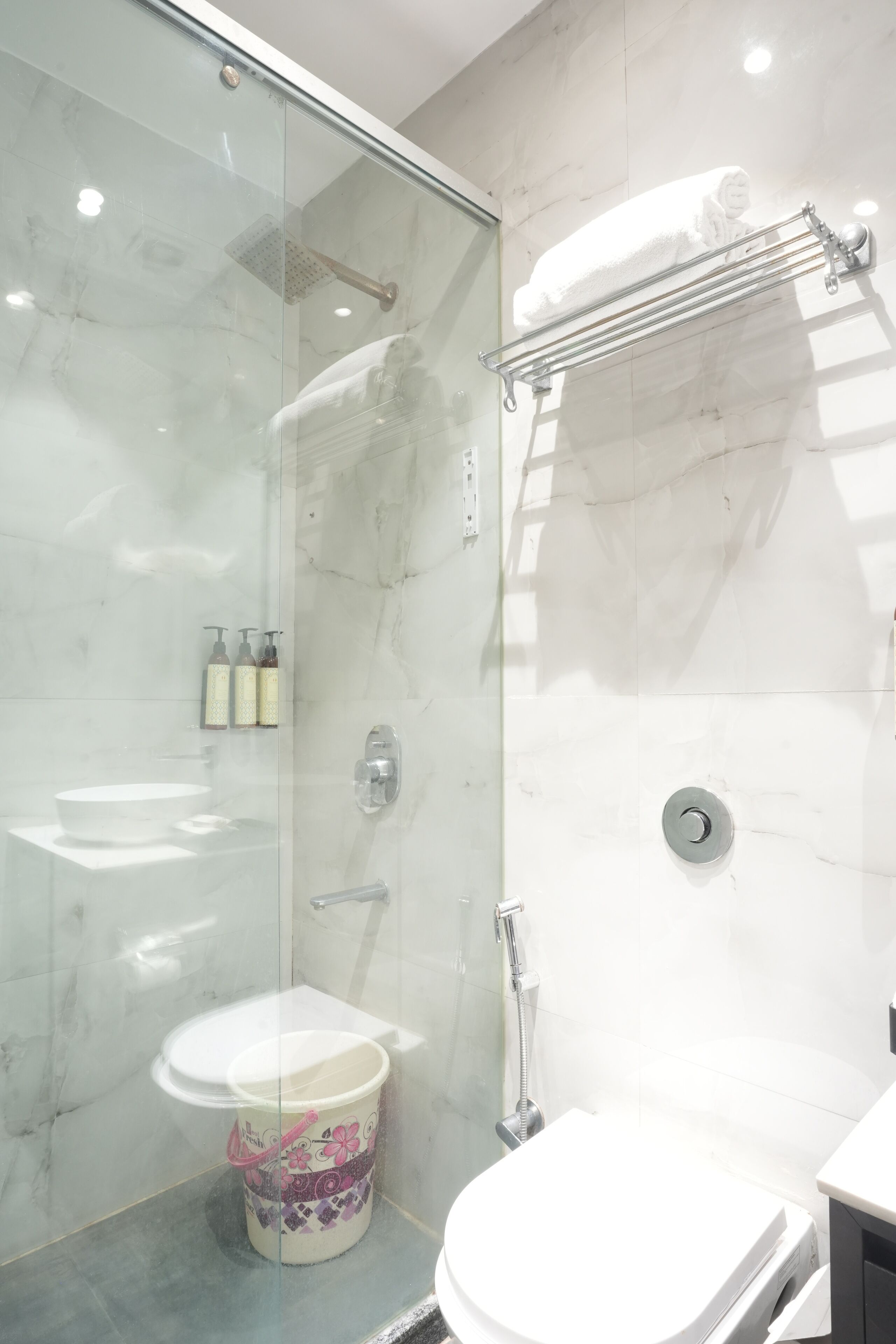A modern bathroom with a glass-enclosed shower, a white sink, and a toilet.