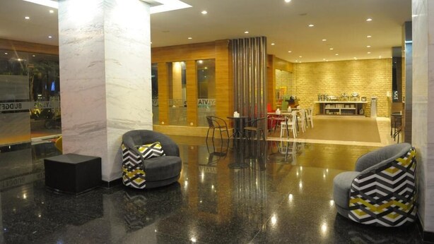 Een moderne lobby met een glazen scheidingswand, een zithoek en een restaurant.
