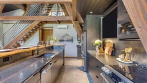 Eine moderne Küche mit einer Granit-Arbeitsplatte, Edelstahlgeräten und einer Holztreppe.
