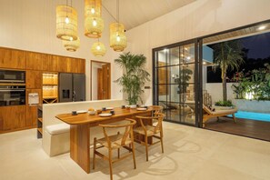 A modern kitchen with wooden cabinetry, a central island, and pendant lighting. - Villa Capture (Pecatu)