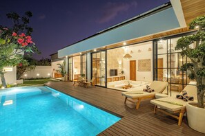 A modern house with a swimming pool, wooden deck, and outdoor seating area. - Villa Capture (Pecatu)