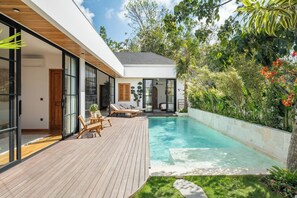 A modern house with a wooden deck, a swimming pool, and lush greenery. - Villa Capture (Pecatu)