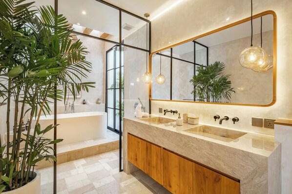 A modern bathroom with a large mirror, wooden vanity, two sinks, and a bathtub. - Villa Capture (Pecatu)