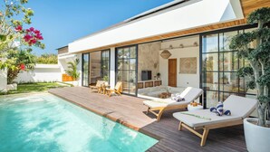 A modern house with a swimming pool, wooden deck, and outdoor seating area.