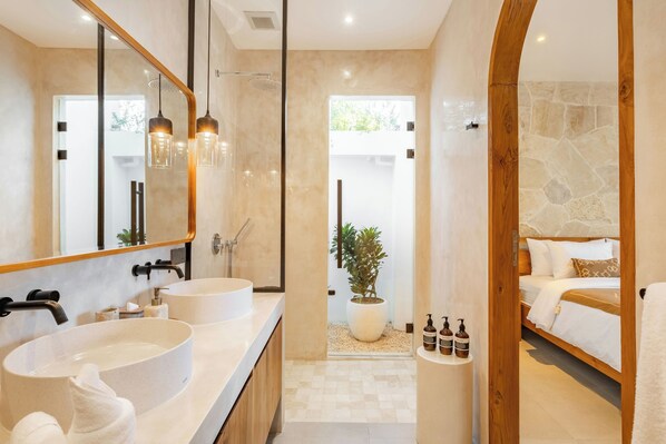 A modern bathroom with two sinks, a large mirror, and a shower area.