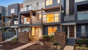 Un edificio residencial moderno de varios pisos con techo plano, ventanas grandes y fachada de piedra.