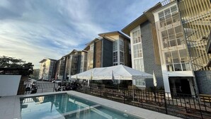 A modern building with a swimming pool, outdoor seating, and a covered area. - Melce Place Studio Unit Condo (Lapu-Lapu City)