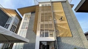 A modern building with a stone facade, large windows, and a covered entrance area with benches. - Melce Place Studio Unit Condo (Lapu-Lapu City)