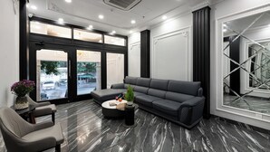 Eine moderne Lobby mit einer schwarzen Ledersofa, einem runden Couchtisch und einer Sitzecke mit einem Blumenstrauß.