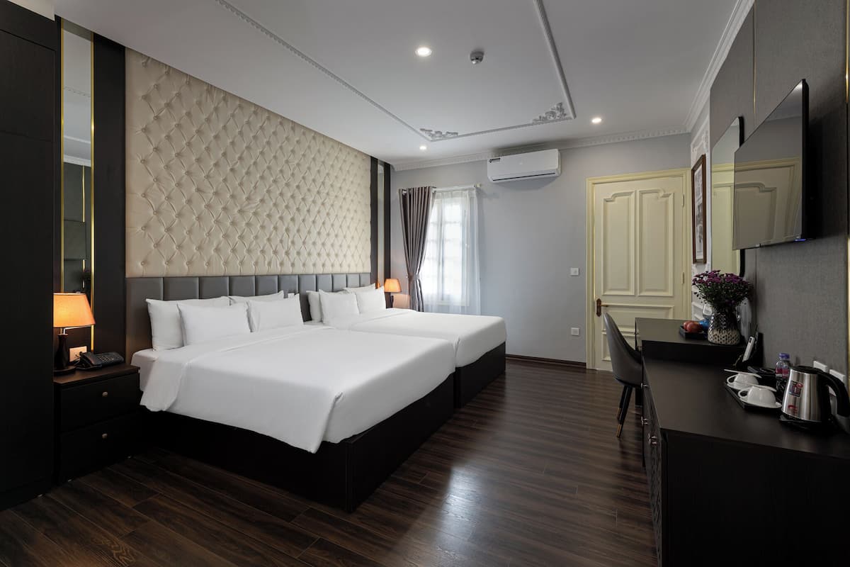 Een hotelkamer met een groot bed, een bureau en een stoel. Op het bureau staat een spiegel, een lamp en een plant.