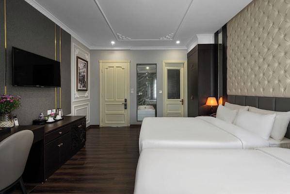 Habitación de hotel con una cama grande, un escritorio con silla, televisión montada en la pared y un baño visible a través de una puerta abierta.