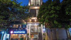 Ein mehrstöckiges Gebäude mit Restaurant im Erdgeschoss, einer sichtbaren Treppe und einer Straße mit fahrenden Fahrzeugen.