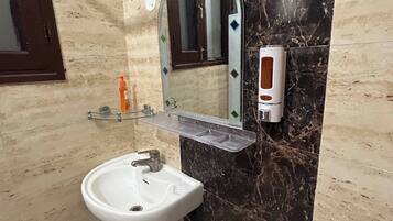 A bathroom with a white sink, a mirror, and a soap dispenser.